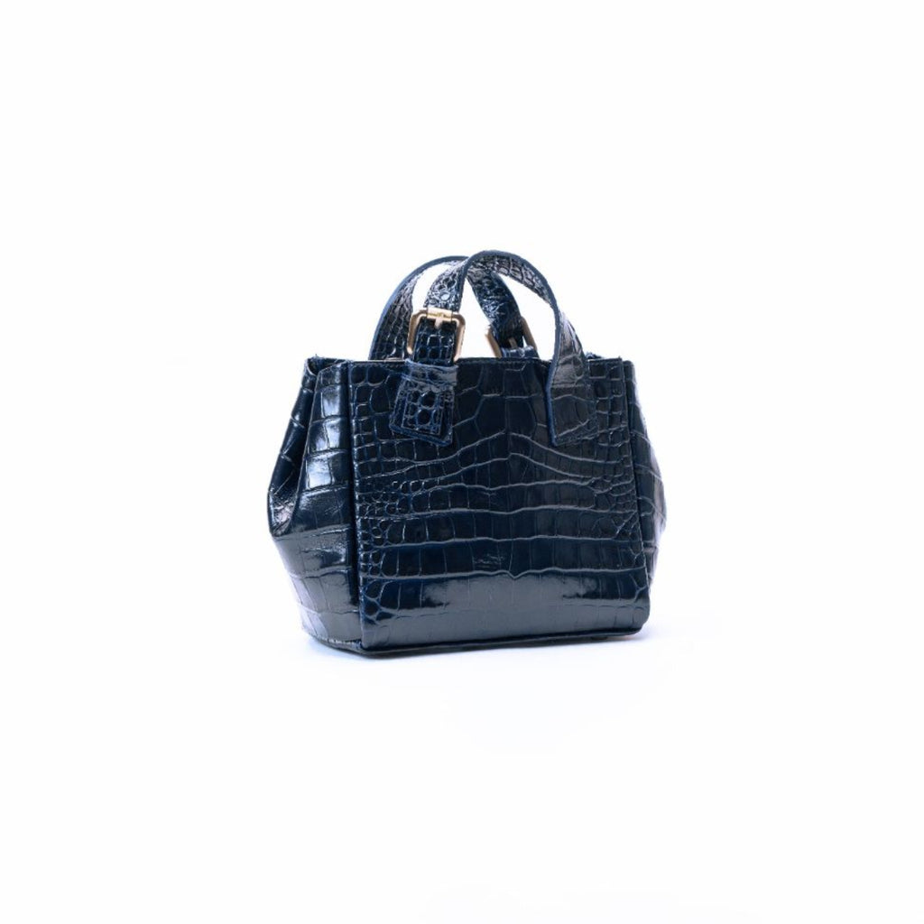 A small structured handbag with a glossy crocodile-embossed texture in black, featuring dual top handles and a gold-tone logo plate on the front, set against a plain white background.