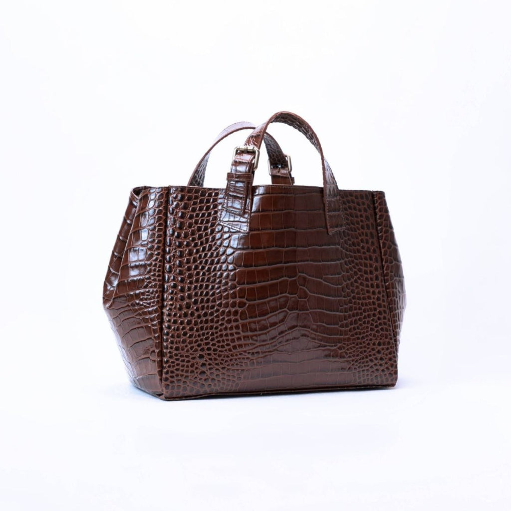 A dark brown crocodile-embossed leather handbag with dual top handles, photographed against a seamless white studio background.