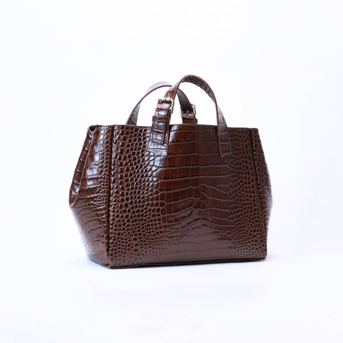 A dark brown crocodile-embossed leather handbag with dual top handles, photographed against a seamless white studio background.