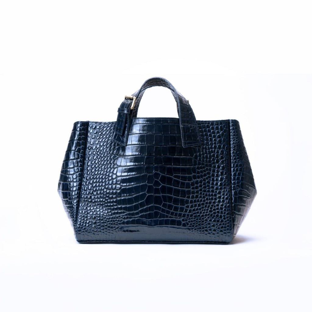 A structured blue crocodile-embossed leather handbag with dual top handles, photographed against a seamless white background.