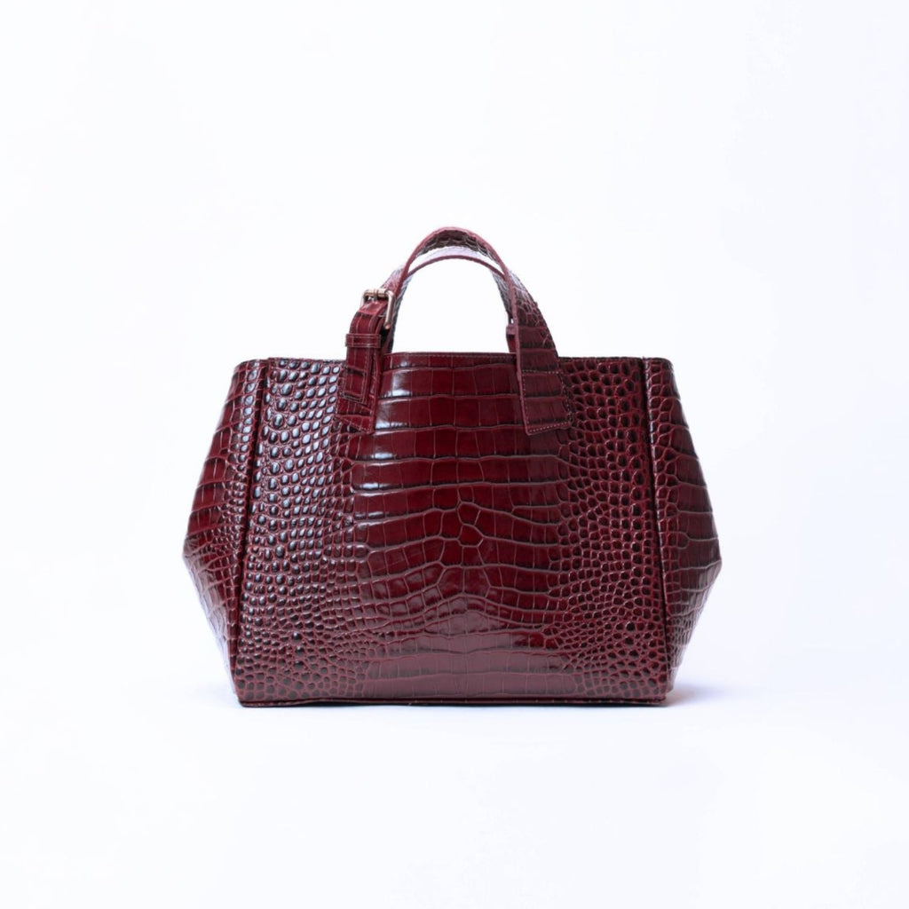 A structured handbag with a glossy crocodile-embossed texture in deep burgundy, featuring two top handles, set against a plain white background.