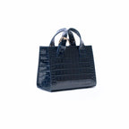 A dark navy blue crocodile-embossed leather handbag with double top handles and gold-tone hardware, shown against a plain white background.