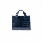 A navy blue crocodile-embossed leather handbag with top handles and a silver-tone buckle, centered on a plain white background.